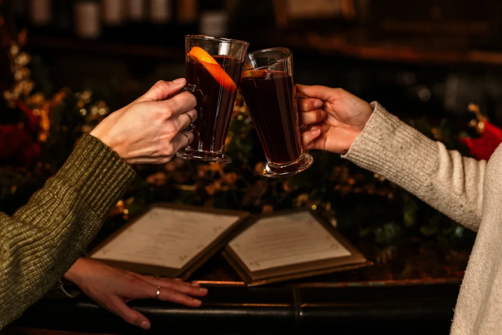 Two people 'cheersing' two glasses of mulled wine